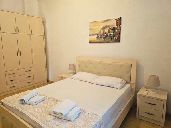 A bedroom with a bed, two bedside tables, a wardrobe, and a painting on the wall.