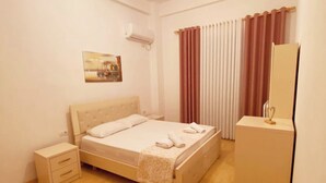 A bedroom with a bed, bedside tables, a wardrobe, a ceiling light, and a wall-mounted air conditioner. - Albania Dream Saranda Apartments (Saranda)