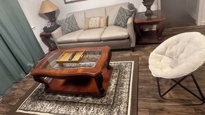 A living room with a sofa, two lamps, a coffee table, a chair, and a rug. - Spacious 4-bedroom apartment with WiFi, AC in charming Conway (Conway)