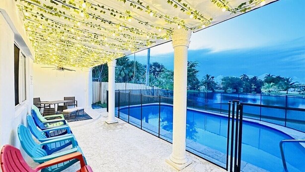 A covered outdoor area with a pool, chairs, and a view of the ocean. - Charming Villa with Pool and Lake View (Miramar)