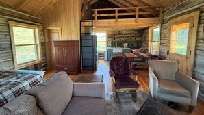 A log cabin interior with a living room, kitchen, and dining area.