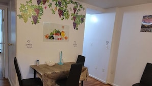 Un coin repas avec une table dressée pour quatre personnes, entourée de chaises.