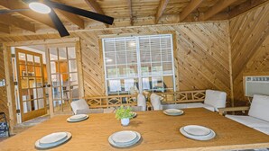 A wooden dining area with a large table set for four, a potted plant, and a view through a large window. - Austin Escape w/ Pool, Hot Tub & Game Room – DT ,Bars, South Congress, Airport ! (Austin)