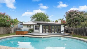 A backyard with a swimming pool, a wooden deck, and a house with a large glass door. - Austin Escape w/ Pool, Hot Tub & Game Room – DT ,Bars, South Congress, Airport ! (Austin)