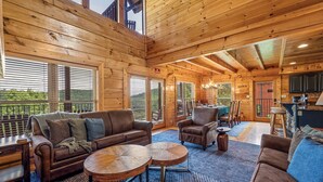 A wooden interior with a sofa, chairs, a dining table, and a kitchen area. - NEW 6BR: Sleep 22| Pool| Views| Cinema| Hot Tub| A+ Location| Dog Friendly (Sevierville)