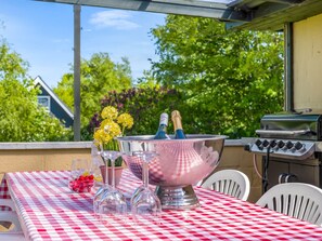 Una mesa con mantel a cuadros, un cuenco metálico con flores, copas de vino y botellas de champán.
