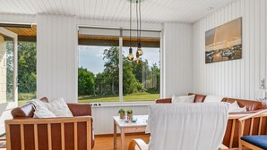 Ein modernes Zimmer mit großem Fenster, Holzmöbeln und einem Gemälde an der Wand.