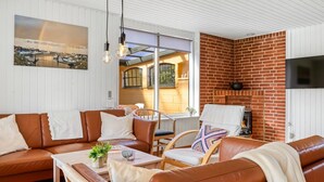 Ein gemütliches Wohnzimmer mit einem Ledersofa, einem Holztisch und einem Kamin aus Ziegelsteinen.
