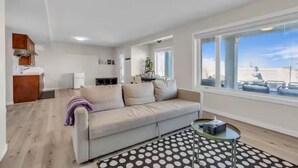 A modern living room with a sofa, coffee table, and a view of the outside.