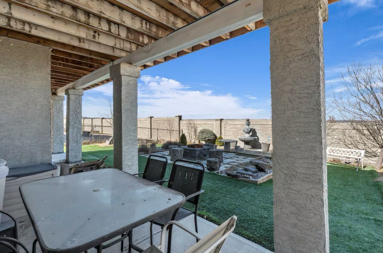 Un espace extérieur aménagé en terrasse, avec une table et des chaises, une fontaine en pierre et un foyer en pierre.