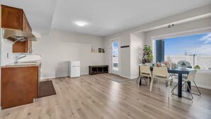 A modern kitchen with wooden cabinets, a white refrigerator, and a dining area with a table and chairs.
