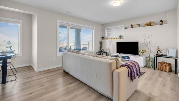 A modern living room with a sofa, TV, and a dining area with a table and chairs.