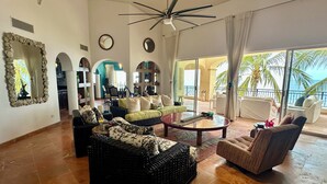 A spacious living area with a large window, a ceiling fan, and a view of the ocean.