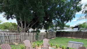 A patio with Adirondack chairs arranged around a stone fire pit. - Haven Retreat-Universal (Orlando)