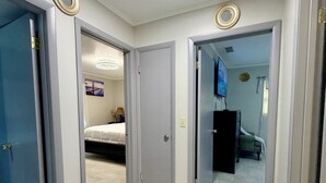 Un passadís amb tres portes que donen a dormitoris, cadascun amb un llit i una televisió.