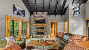 A cozy living room with a stone fireplace, leather sofas, and a wooden coffee table.