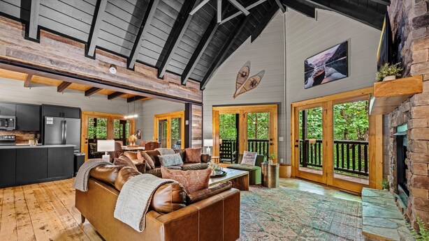 A spacious living area with a wooden ceiling, a large sofa, a coffee table, and a fireplace.