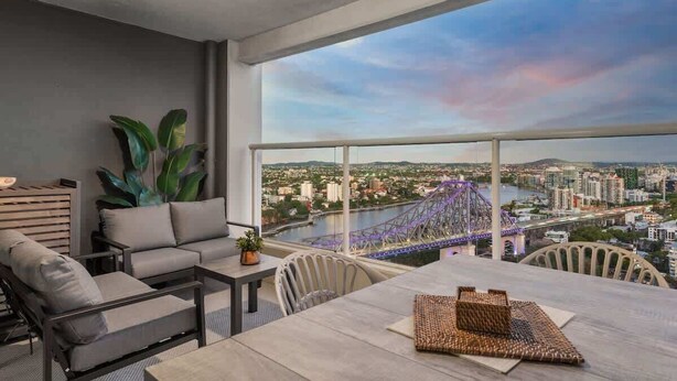 A balcony with a city view, a sofa, a table, and a chair.