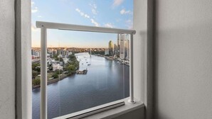 A window with a view of a river, buildings, and a bridge.