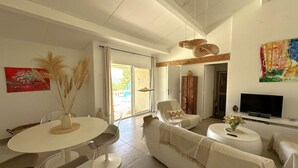 A spacious living room with a dining area, a sofa, a TV, and a painting on the wall.