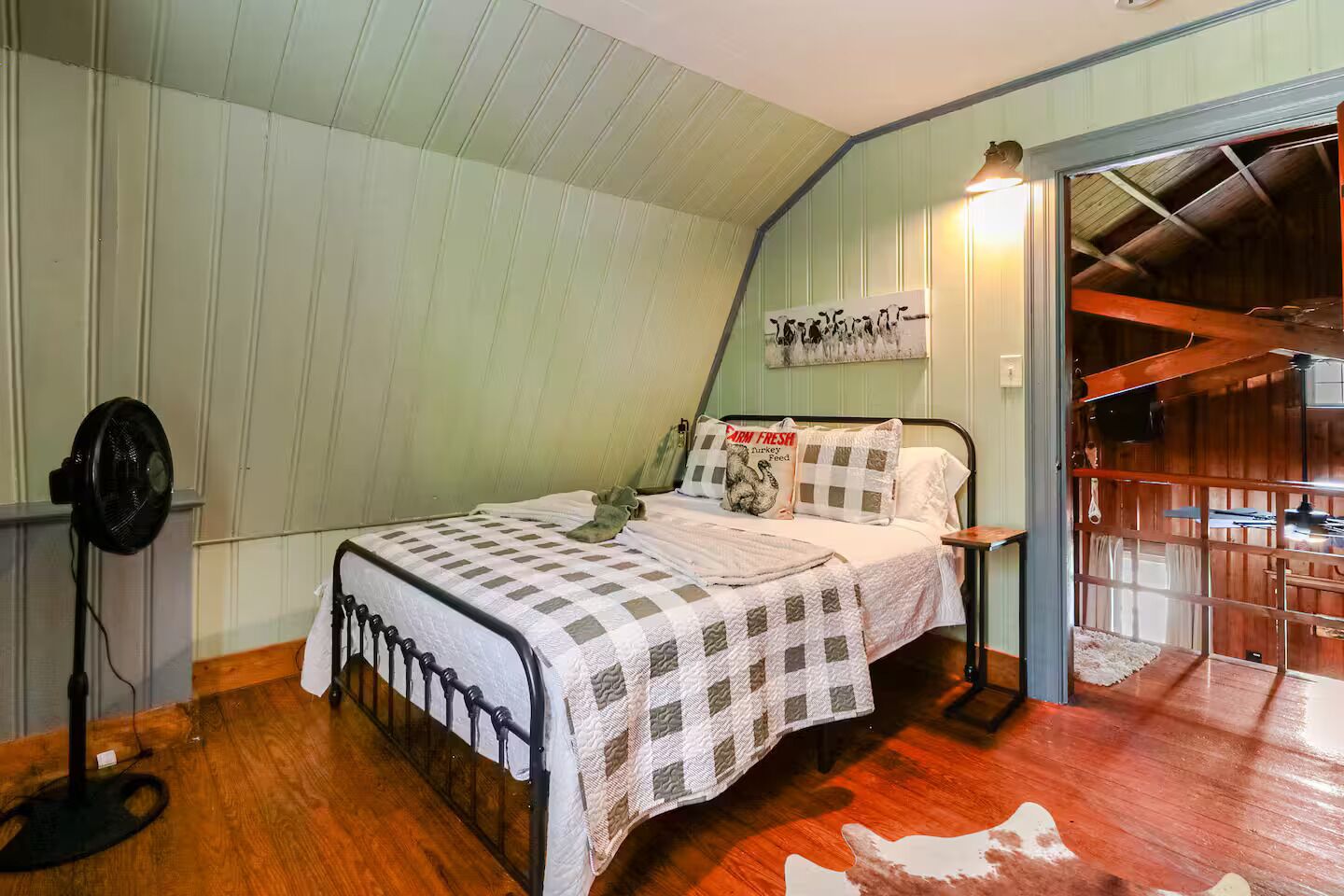 Une chambre à coucher comprenant un lit, une table de chevet, un ventilateur fixé au mur et un ventilateur de plafond.