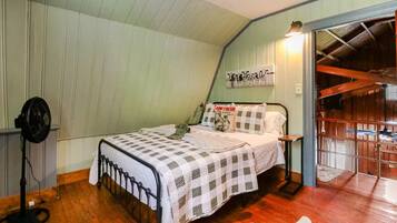 Une chambre à coucher comprenant un lit, une table de chevet, un ventilateur fixé au mur et un ventilateur de plafond.