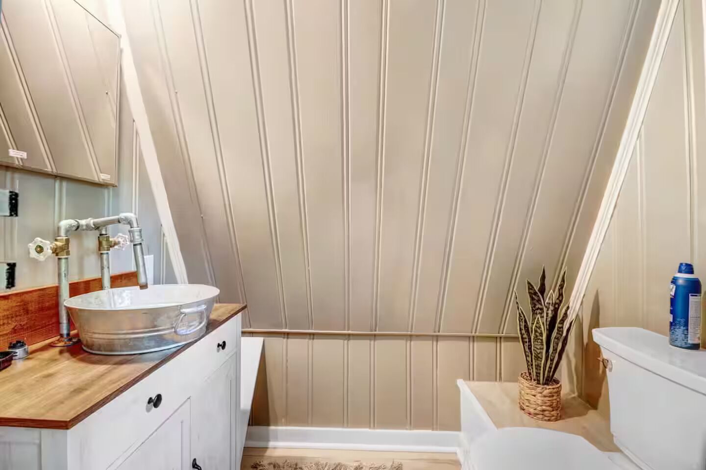 Un baño con tocador de madera, lavamanos blanco, espejo y retrete.