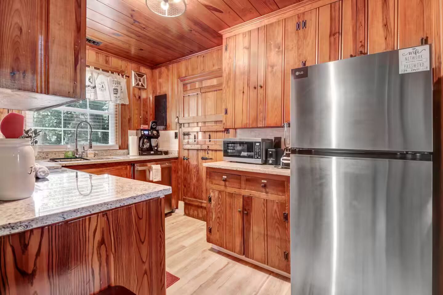 A kitchen with wooden cabinets, a stainless steel refrigerator, a microwave, and a coffee maker.