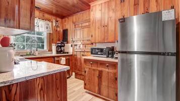 A kitchen with wooden cabinets, a stainless steel refrigerator, a microwave, and a coffee maker.