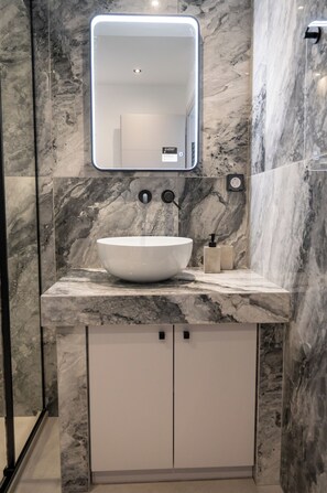 A bathroom with a marble sink, a mirror, and a built-in cabinet.