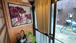 Een kamer met een houten wand, een ingelijst schilderij, een plant in pot en een fiets voor de deur.