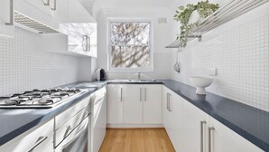 Een moderne keuken met witte kasten, een zwart aanrecht en een raam met uitzicht op bomen.
