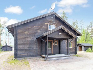 Une cabane en bois avec une antenne parabolique, une véranda et un petit abri attenant.