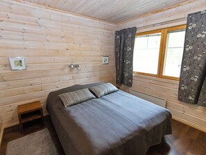Ein Schlafzimmer mit einem Bett, einem Fenster mit Vorhängen und Holzwänden.