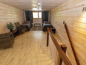 Ein Interieur einer Holzhütte mit zwei Betten, einer Bank, einem Stuhl und einem Blumentopf.