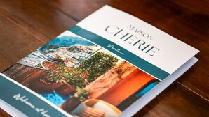 Une brochure intitulée « Maison Chérie Provence » est posée sur une table en bois.