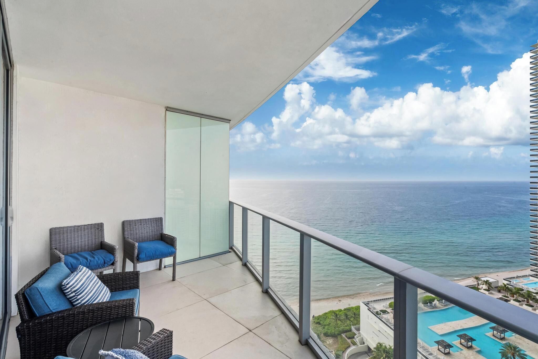 A balcony with wicker furniture and a view of the ocean.