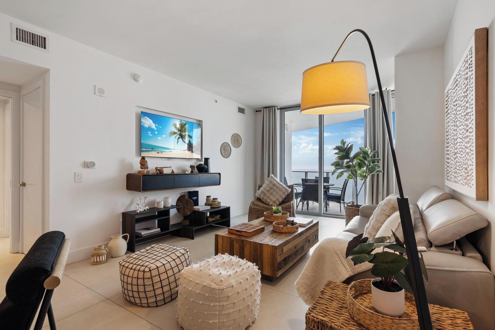 A modern living room with a flat-screen TV, a sofa, a coffee table, and a floor lamp.