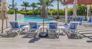 Zona junto a la piscina con sillas de descanso y sombrillas.