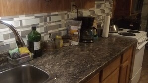 A kitchen with wooden cabinets, a granite countertop, a stainless steel sink, a coffee maker, and a stove. - Charming 1-bedroom unit in gorgeous Custer with WiFi car rental available. Suite (Custer)