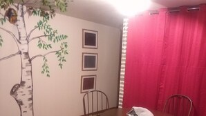 A dining area with a round table, four chairs, a wall mural of a tree, and three framed pictures. - Charming 1-bedroom unit in gorgeous Custer with WiFi car rental available. Suite (Custer)