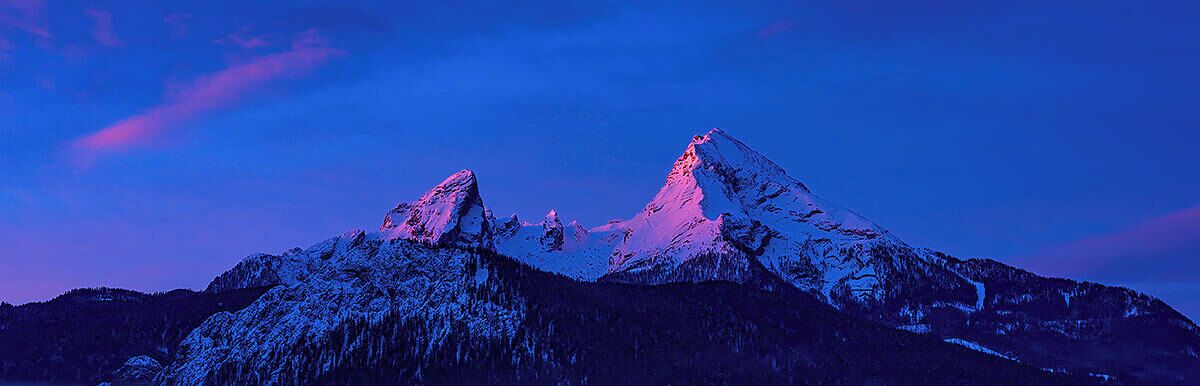A mountain range with snow-covered peaks and a clear sky.