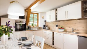 Een moderne keuken met witte kastjes, een houten aanrechtblad en een eethoek voor zes personen.
