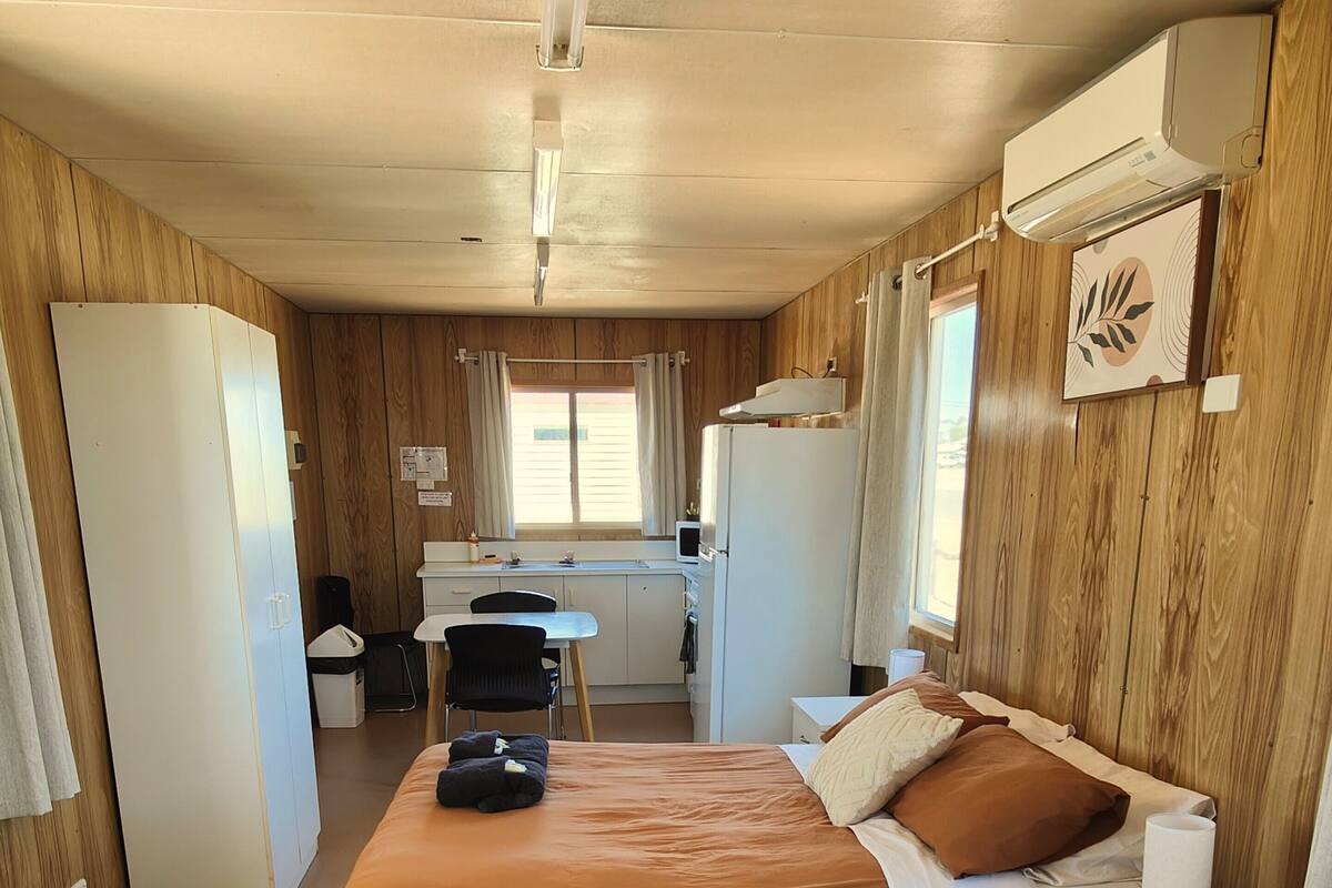 A compact room with two beds, a small kitchenette, and a window.