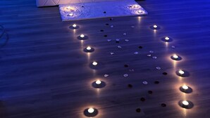 A bedroom with a bed, heart-shaped wall decorations, and a floor with illuminated candles.