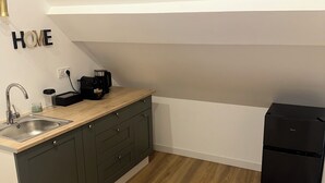A compact kitchen with a sink, countertop, and a black refrigerator.