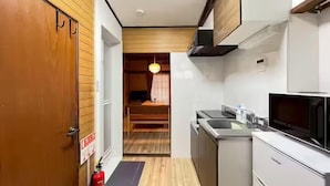 A compact kitchen with a microwave, sink, and wooden cabinets. - Akabanenishi Kodate (Tokyo)