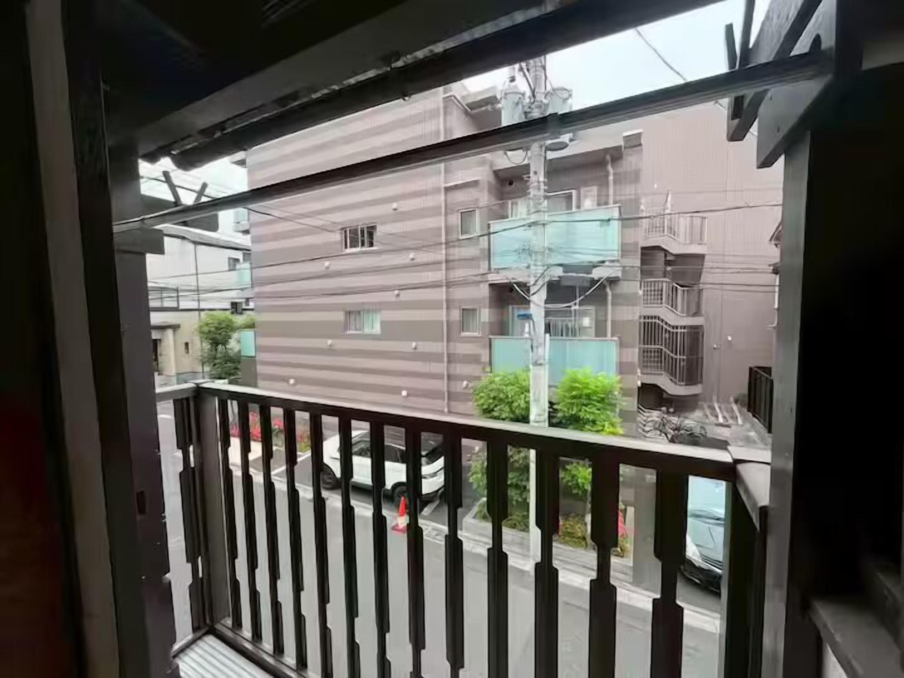 A view from a balcony overlooking a residential building with a modern design, featuring multiple balconies and a clear street view.