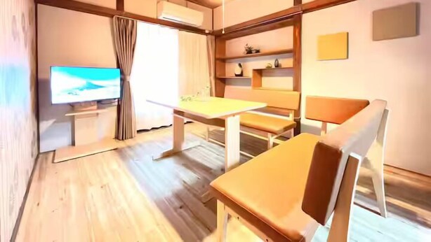 A room with a wooden floor, a table with chairs, a television, and shelves with decorative items. - Akabanenishi Kodate (Tokyo)