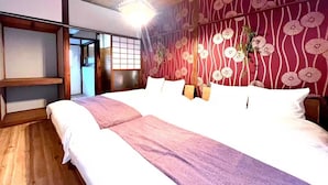 A hotel room with a large bed, wooden flooring, a decorative wall with a floral pattern, and a traditional Japanese sliding door. - Akabanenishi Kodate (Tokyo)